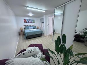 a bedroom with a bed and a couch and a mirror at The Love Shack in Bongaree