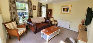 a living room with a couch and chairs and a tv at Conifer Cottage in North Somercotes +6 photos