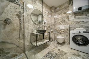 a bathroom with a shower and a washing machine at Apartments Penthouse lux XYZ in Rogoznica