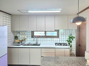 a kitchen with white cabinets and a sink at 머물다 울산 울산공항 5분 태화강역10분 울산 병영성 in Ulsan