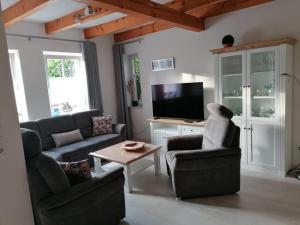 a living room with two couches and a tv at Haus Tenne in Krummhörn