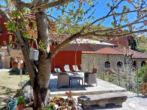 a patio with a tree and a table and chairs at Camerana La Casa Rossa in Camerana 