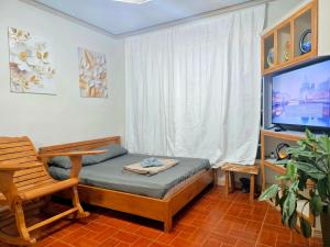 a bedroom with a bed and a tv and a chair at 35 Amistad Guesthouse in Baguio