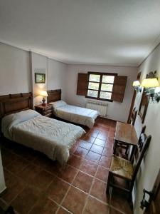 Un dormitorio con dos camas y una mesa dentro. en Albergue el Caseron de Fuentes Carrionas, en Cardaño de Abajo