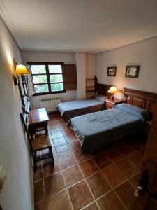 1 dormitorio con 2 camas, mesa y 2 lámparas en Albergue el Caseron de Fuentes Carrionas, en Cardaño de Abajo