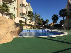a swimming pool with green grass next to a building at Spanish Connection - Cala Azul in Cabo de Palos