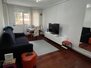 a living room with a couch and a flat screen tv at Apartamento con piscina de junio a septiembre y a 100 m de la playa in Castro-Urdiales