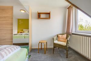 a bedroom with a bed and a chair and a window at Wohnung Hallighof in Honkenswarft