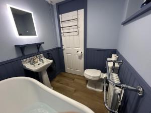 a bathroom with a tub and a sink and a toilet at Halcyon House in Bodham +17 photos