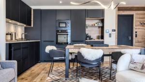 a kitchen with black cabinets and a wooden table and chairs at Appartement La Terrasse in Les Houches