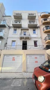 a red car parked in front of a building at FP Spinola Whole Apartment - FREE WI-FI in St Julian's