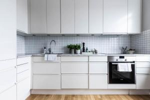 a white kitchen with white cabinets and appliances at Biz Apartment Gärdet in Stockholm