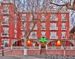 un edificio rojo con un cartel delante en Hotel Nuevo Palas, en Lanjarón