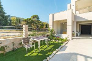 a patio with a table and chairs on the side of a house at Aura Luxury Suites - Olympiada Seaside Accessible Friendly in Olympiada +57 photos