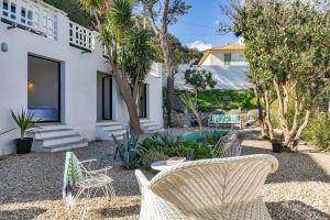 ein Hinterhof mit Stühlen, einem Tisch und Bäumen in der Unterkunft Villa sur la plage Cap Corse in Brando