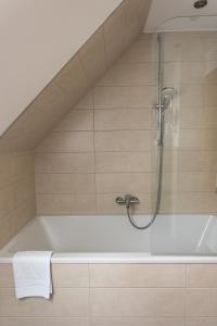 a bath tub with a shower in a bathroom at Restaurant und Hotel Alte Schule Fürstenhagen in Fürstenhagen +47 photos