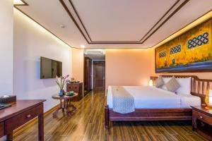 a hotel room with a bed and a tv at Fivitel Hoi An Hotel in Hoi An