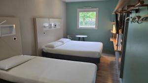 a small room with two beds and a window at ibis budget Goussainville Charles de Gaulle in Goussainville +142 photos