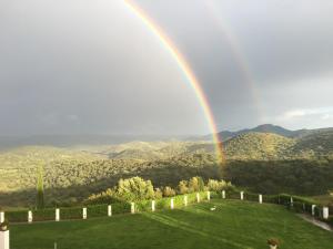 a rainbow over a green field with mountains in the background at Casa Vesta in Zufre