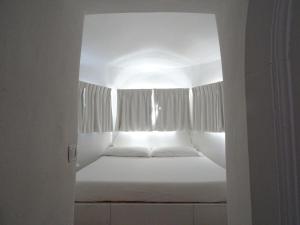 Una cama blanca en una habitación con ventana. en La Casa del Faro, en Porto Ercole