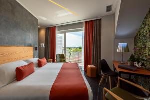 a hotel room with a bed and a desk and a window at Wellness Spa Hotel Principe Fitalia in Syracuse