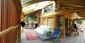 a porch of a wooden house with a couch and chairs at Wild and off-the-grid with style in Zuurbraak
