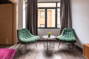twee groene stoelen en een tafel in een kamer bij Industrial-Style Apt in Psyrri, Walk to Acropolis in Athene