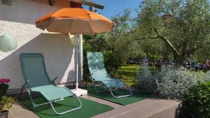 two chairs and an umbrella on a lawn at Holiday house in Pula
