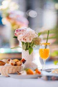 a table with a vase of flowers and a glass of orange juice at Boutique Hotel Townhouse 27 in Belgrade