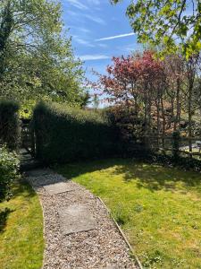 a garden with a hedge and a walk way at Gardeners Cottage in Mudford +8 photos
