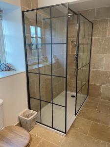 a shower with a glass door in a bathroom at Gardeners Cottage in Mudford