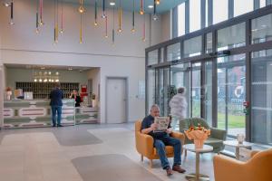 a man sitting in a chair in a lobby at DOMITYS - La Flânerie in Béthune +27 photos