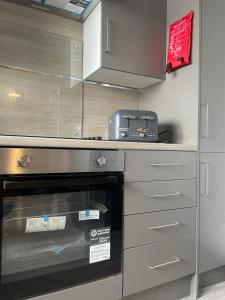 a kitchen with a stove top oven in a kitchen at 1 Bed Flat with King or Twin Beds, Sofa Bed, Work space, Dining and SMART TV with Free Wifi Throughout! in Wingate