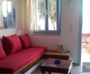 a living room with a red couch and a table at Asvestoti blue ciel light 2 in Pera Gyalos