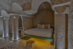 a bedroom with a bed in a stone room at Eka Cave Maison Authentic Cave Boutique Hotel in Cappadocia Village in Nevşehir +96 photos