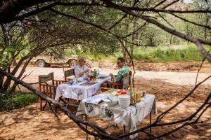 two people sitting at a table in the shade at Ohorongo Safari Lodge in Kamanjab
