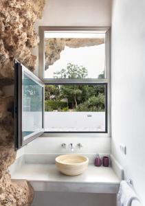 un bagno con una grande finestra con una ciotola di legno di Cuevas del Pino Turismo Rural y Emocional SL a Villarrubia