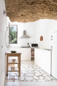 uma cozinha com armários brancos e uma mesa em Cuevas del Pino Turismo Rural y Emocional SL em Villarrubia