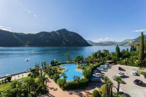 a view of a lake with palm trees and a resort at The Lac View in Bissone +5 photos