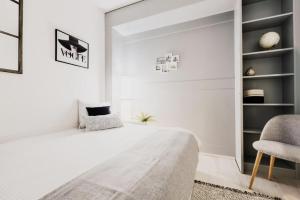 a white bedroom with a bed and a chair at The Lac View in Bissone