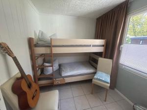 リーブニッツ・ダムガルテンにあるFerienhaus am Küstenwaldの二段ベッドとギターのある部屋