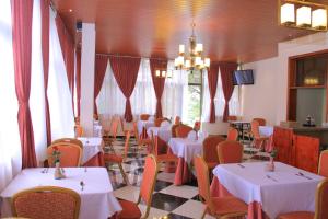 ein Esszimmer mit weißen Tischen und orangefarbenen Stühlen in der Unterkunft Hotel Lobelia in Addis Abeba