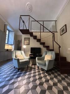 ein Wohnzimmer mit 2 Stühlen und einer Treppe in der Unterkunft Palazzo Mormorai in Florenz