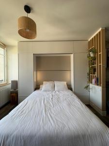 a bedroom with a large white bed with a headboard at Charmant studio avec terrasse hyper-centre de Vannes à 5 min du Port et des Remparts in Vannes