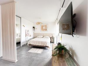 a white bedroom with a bed and a mirror at Appartement Eléa, Vue sur Mer, T1 sur Fréjus à 150m des plages in Fréjus
