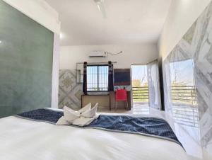 a bedroom with a large white bed and a red chair at Hotel Hari Om in Diu