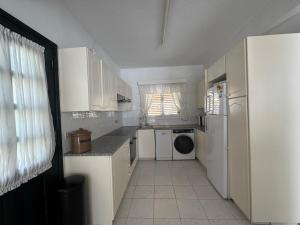 a small kitchen with white cabinets and a refrigerator at New cozy Villa near the beaches in the Magnificent Gardens of Regina with swimming pools! in Paphos City