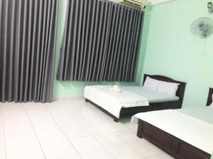a hotel room with two beds and a window at Thanh Tùng Hotel HCM in Ho Chi Minh City