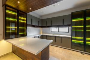 an empty kitchen with a white counter top and wooden cabinets at M72 Luxe 1 Kanal Modern House Phase 6 DHA Raya in Lahore +115 photos