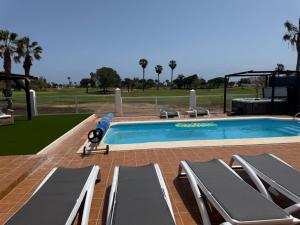 una piscina con diverse sedie a sdraio e una piscina di Vista Verde, Luxury Family Front Line Golf, Hot Tub,Pool Table, 8 pers, Caleta de Fuste a Caleta De Fuste